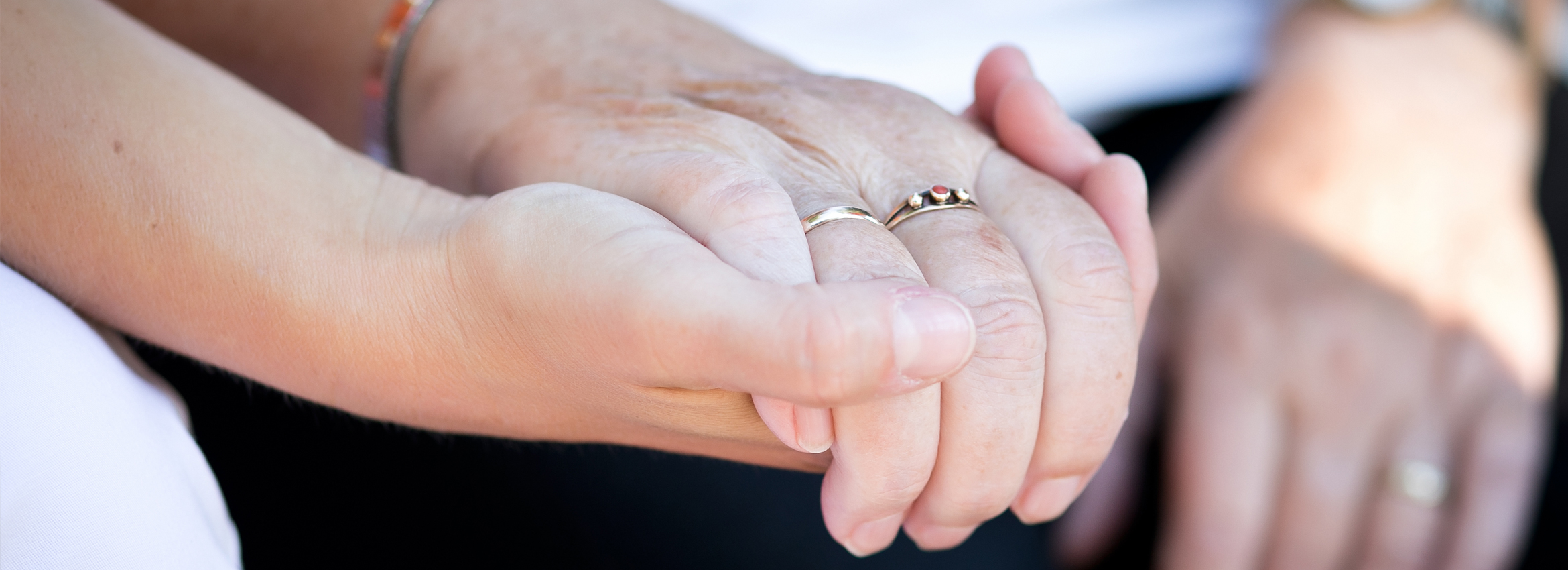 Die Hand einer Pflegerin h&auml;lt die Hand einer Seniorin und spendet Geborgenheit und W&auml;rme